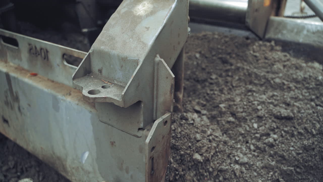 Asphalt unloaded from wheelbarrow. Paver at asphalt pavement works for road under construction