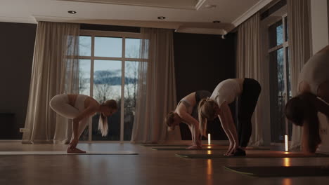 group of young woman practicing yoga with the help of an instructor. they are doing seated side twist asana. in a bright room.