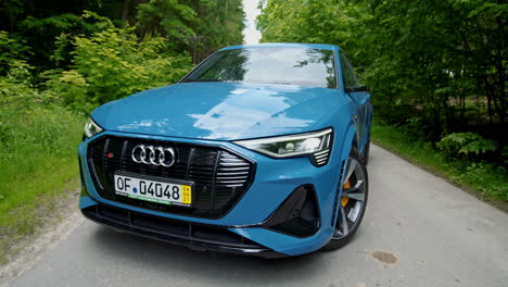 e-tron logo on audi car. modern design of a new electronic car blue color. presentation of a luxury audi on green nature background.