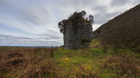 Panorama-motion-timelapse-of-rural-nature-farmland-with-ancient-boulder-rock-and-trees-in-the-foreground-bog-grassfield-during-cloudy-day-viewed-from-Carrowkeel-in-county-Sligo-in-Ireland