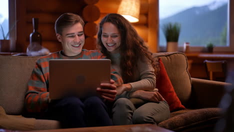happy couple watching laptop together on a cozy couch