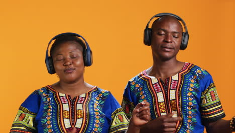 cheerful ethnic people playing air guitar with music on headset