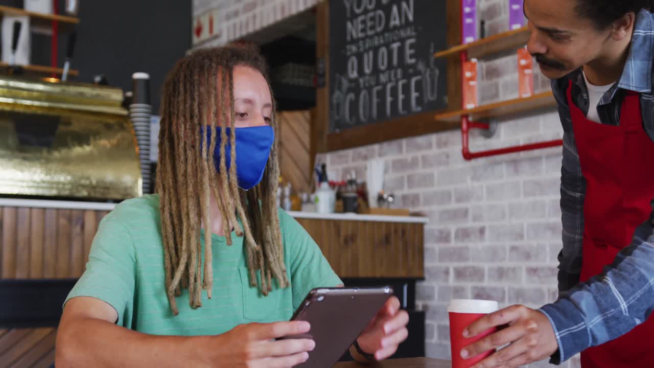 barista de raza mixta con dreadlocks sirviendo café al cliente