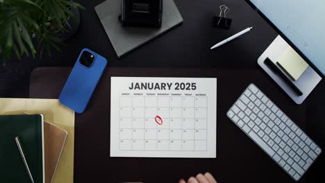 person marking a date on a 2025 january calendar