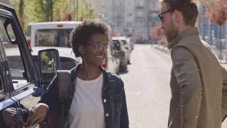 an young woman and a young man have a conversation next to a van before a road trip