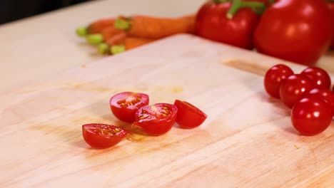 hand selects tomatoes from a wooden cutting board