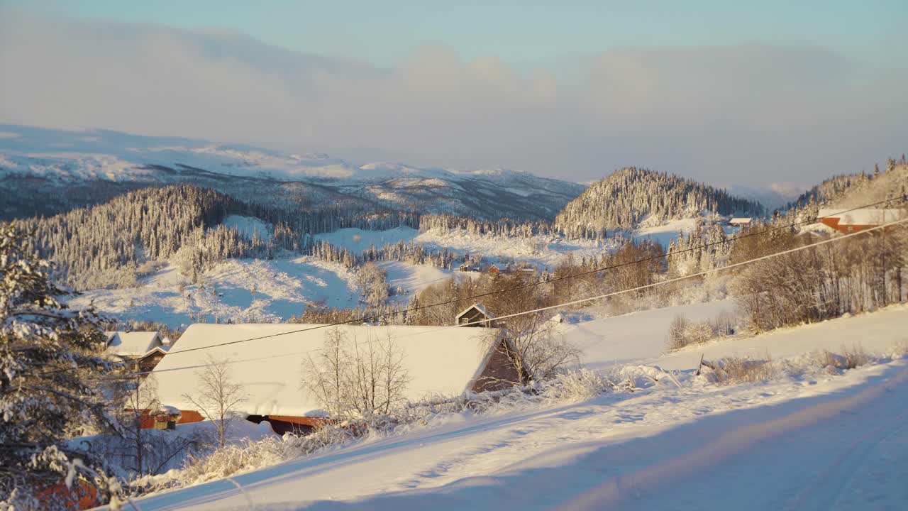 하늘에서 클라우드스케이프와 함께 황금빛 일몰 동안 눈 덮인 겨울 풍경의 공중 와이드 샷