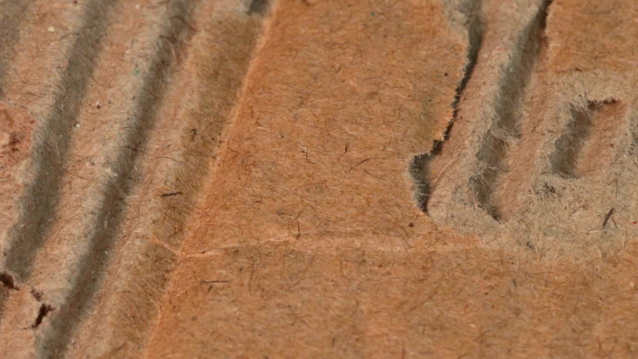 Macro shot of torn cardboard from very close up view and rotation motion.