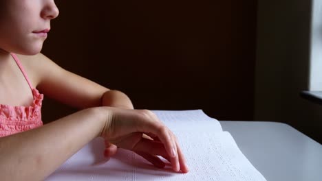 schoolgirl reading a braille book in classroom