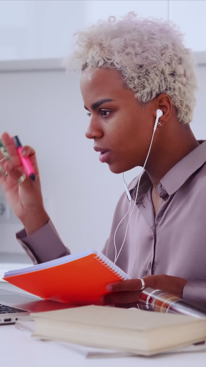 Young professional wearing earbuds and concentrating while taking notes in