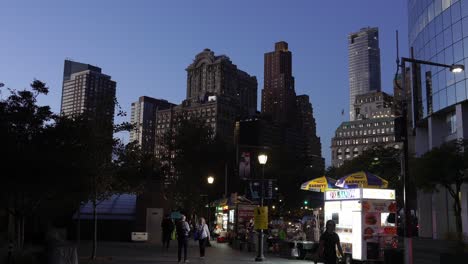 wall street at dusk, with quiet streets and a few pedestrians walking past the iconic buildings