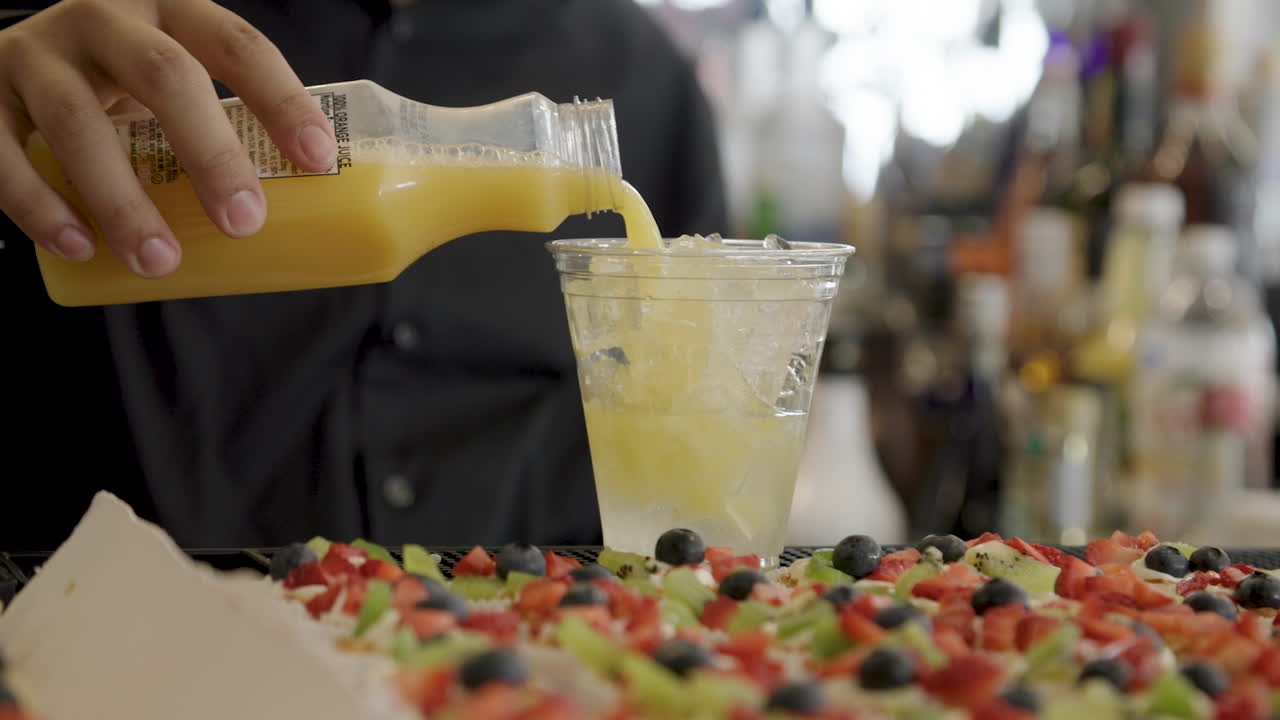 bartender pouring orange juice mixing drinks
