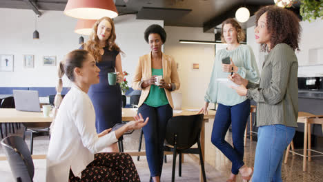 diverse businesswomen having casual meeting, talking and using tablet at office, in slow motion