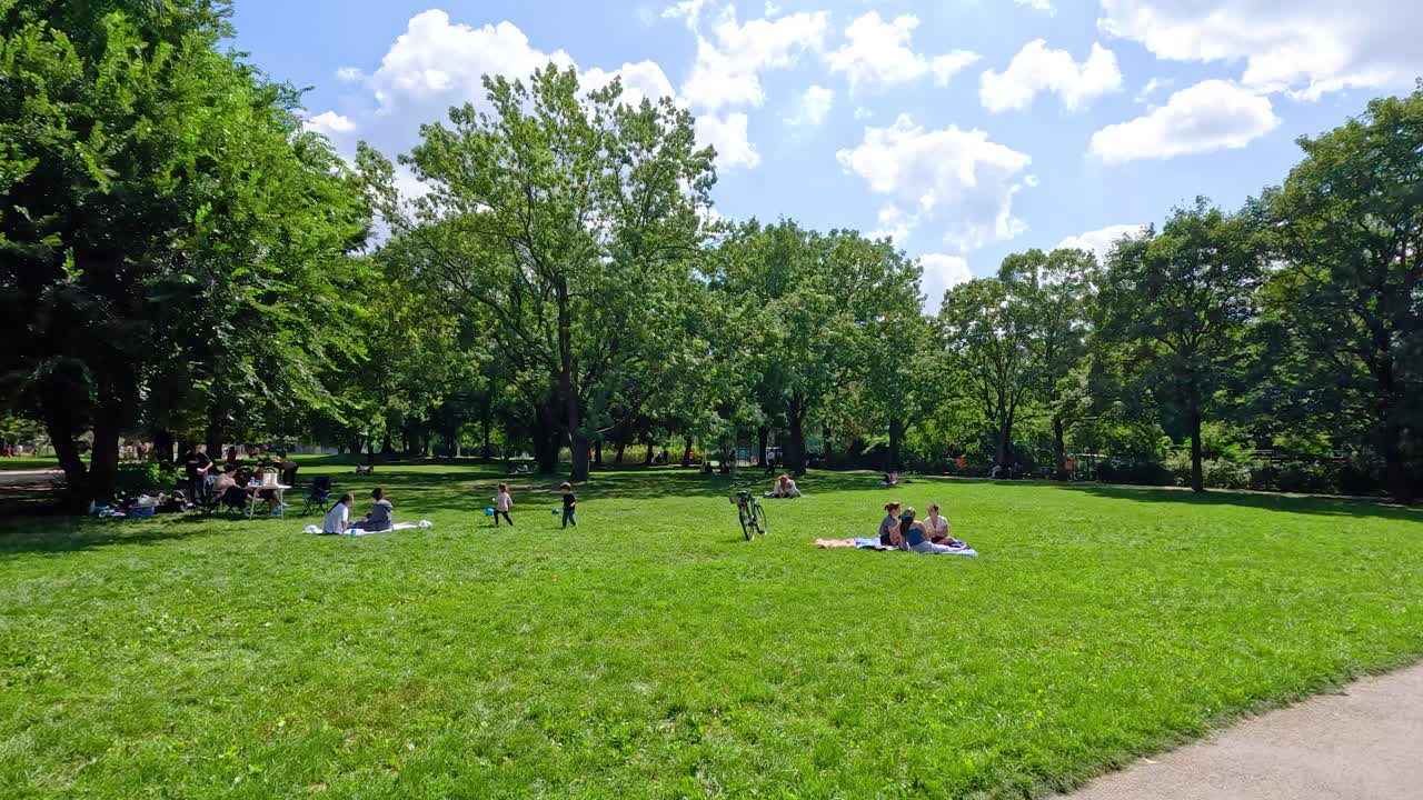 Steady walk along a paved path in a green city park with people relaxing outdoors