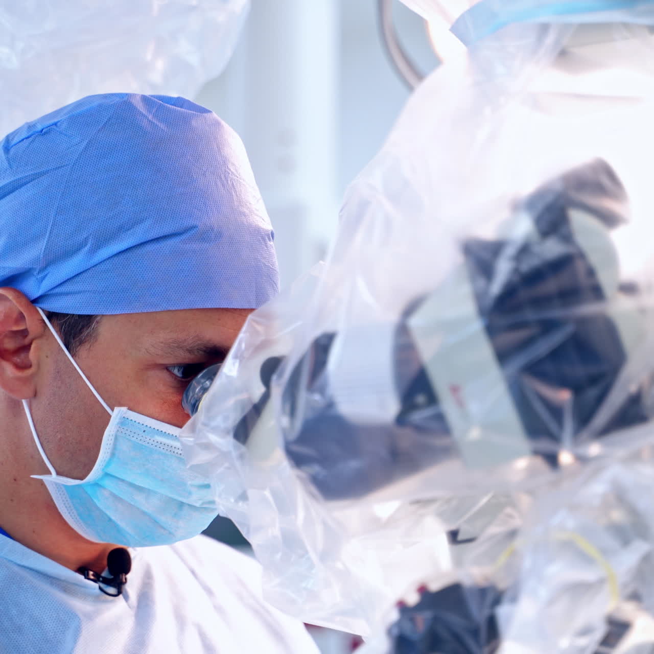 Surgery through modern equipment. Side view of surgeons in protective uniform looking into the microscope. Close-up faces of doctors in masks.