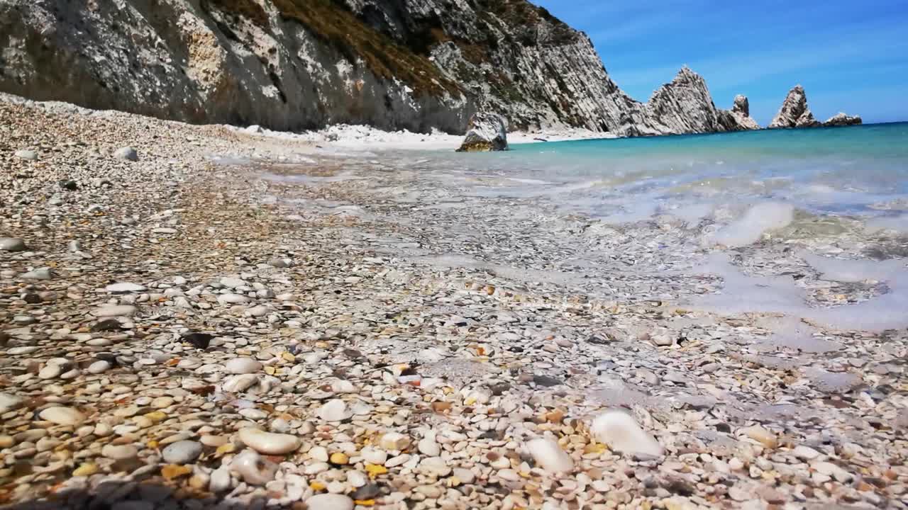 Spiaggia delle Due Sorelle di Numana con ciottoli colorati e onde