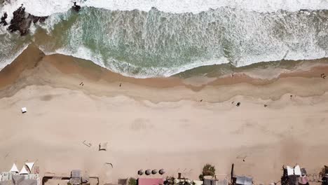 Vista-Aérea-De-Un-Pequeño-Pueblo-Costero-En-México,-Olas-Rompiendo-Contra-La-Orilla,-Gente-Caminando