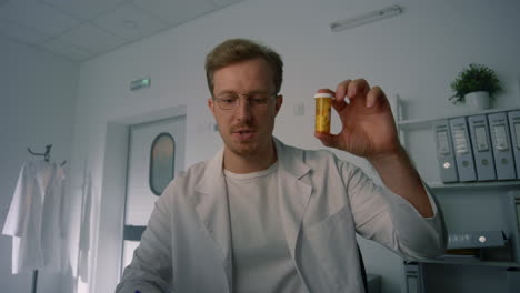 therapist holding pill bottle at online consultation in health clinic close up.