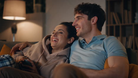 cute couple watching movie in cozy apartment at night close up. family enjoy tv.