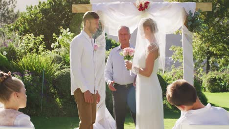 La-Novia-Y-El-Novio-Caucásicos-De-Pie-En-El-Altar-Al-Aire-Libre-Con-El-Oficiante-De-Bodas-Durante-La-Ceremonia.