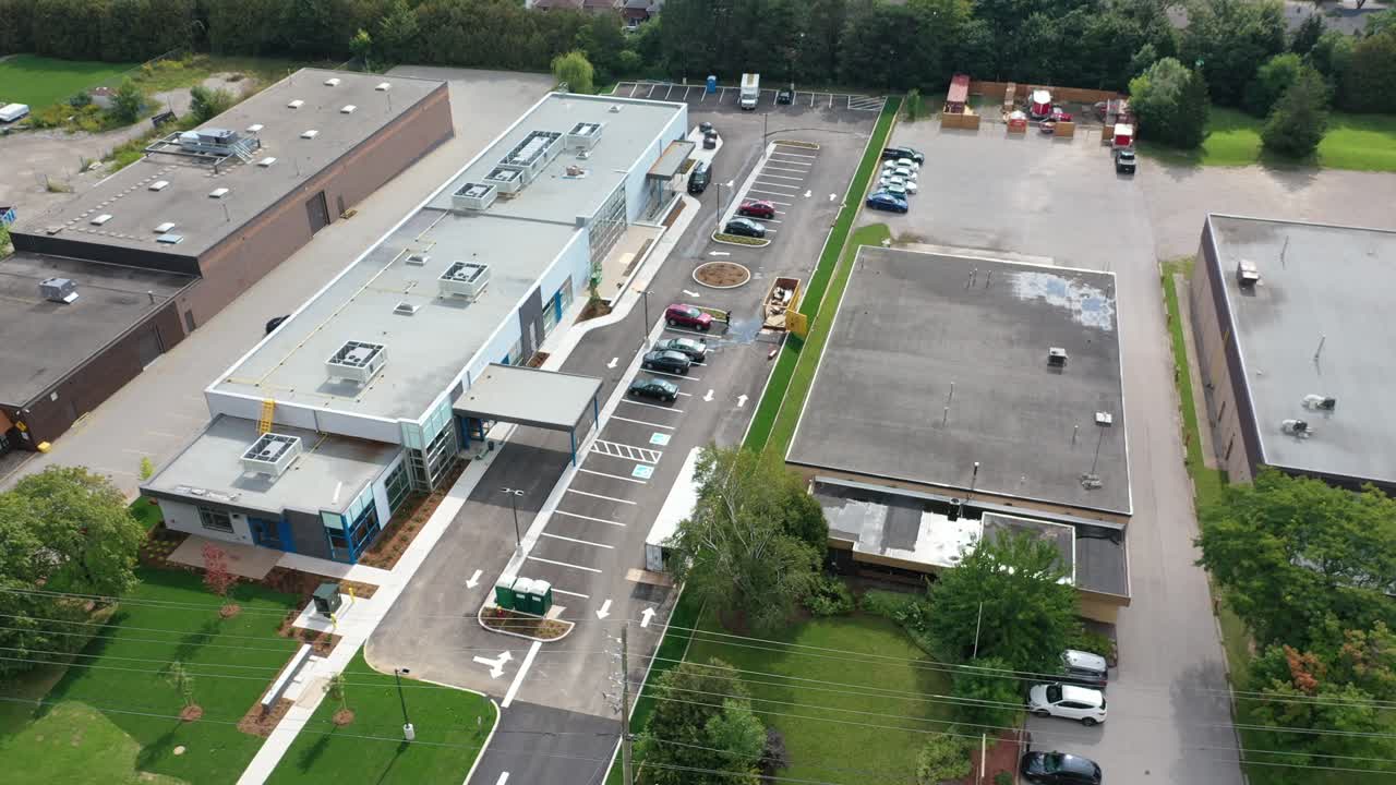 Vista aérea en ángulo alto de un moderno edificio comercial y un parque industrial, donde se ven almacenes, aparcamientos y calles en un típico distrito comercial suburbano estadounidense
