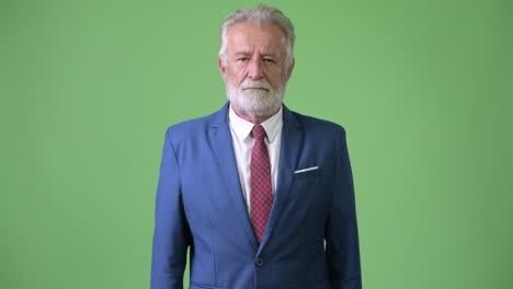 hombre de negocios barbudo y guapo contra un fondo verde.