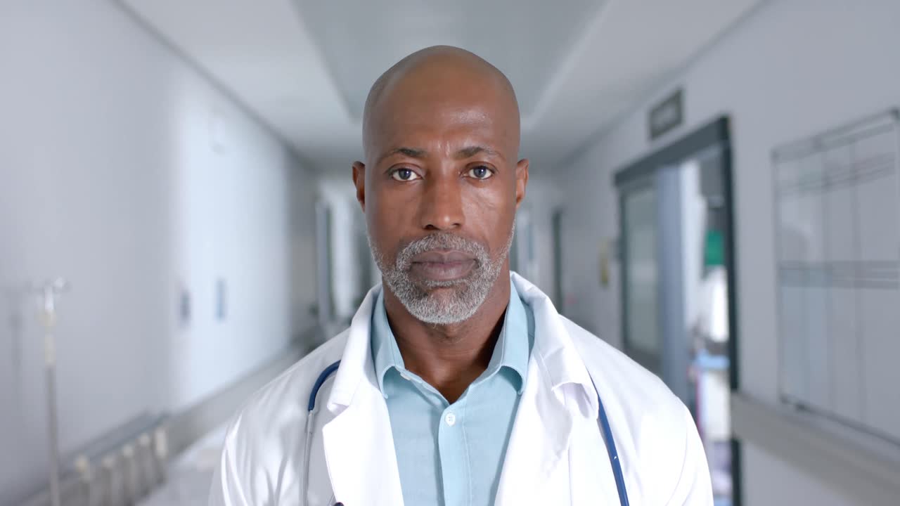Portrait of african american male doctor wearing lab coat and stethoscope at hospital, slow motion