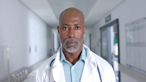 Portrait-of-african-american-male-doctor-wearing-lab-coat-and-stethoscope-at-hospital,-slow-motion