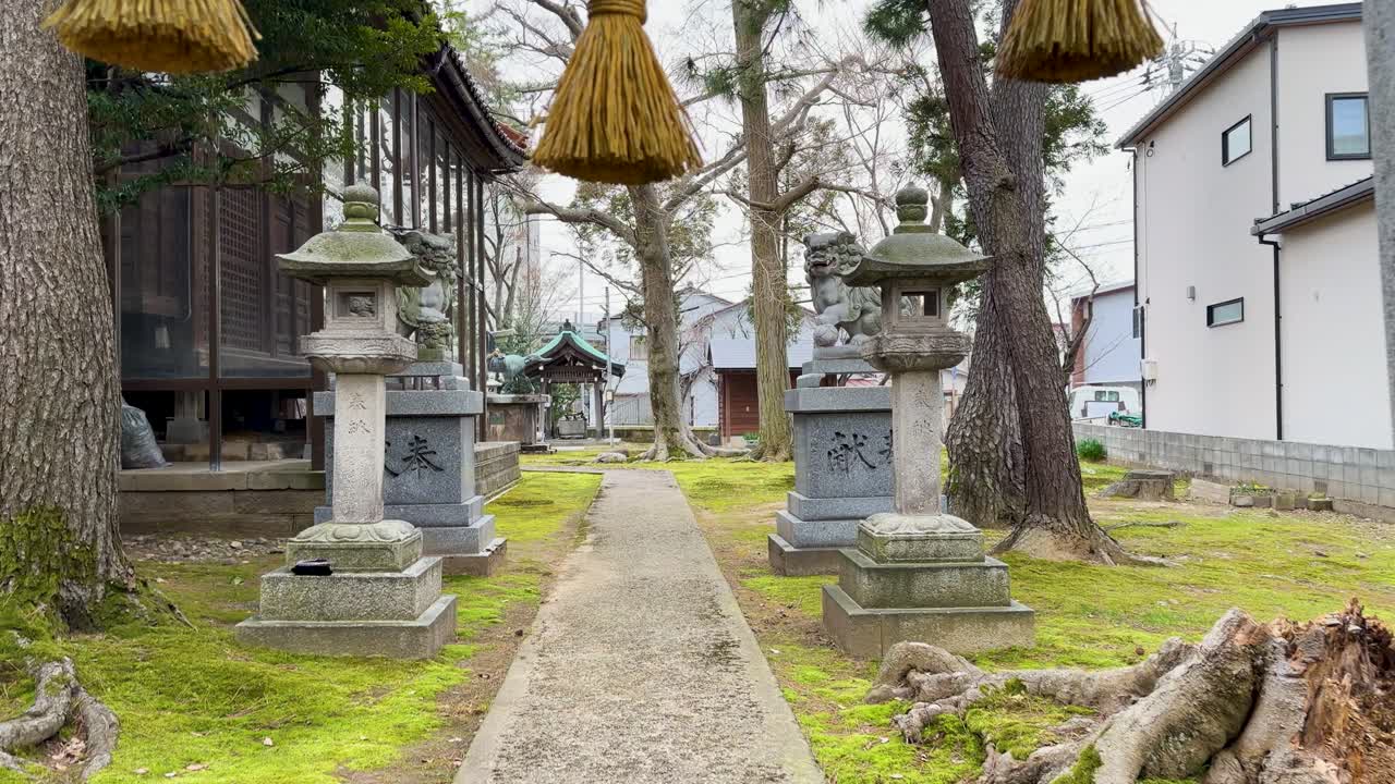A slow forward camera movement through a traditional Japanese shrine entrance with stone lanterns