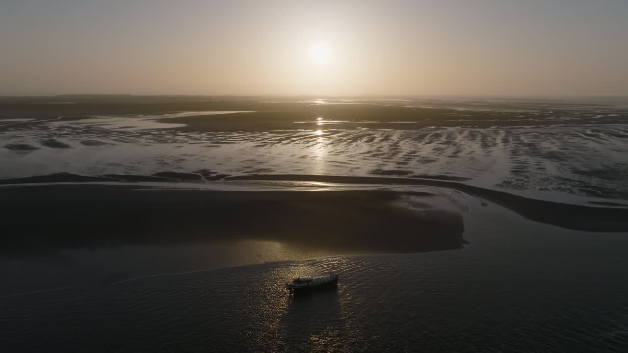Wide coastal overview at daybreak with a luxemotor boat resting on the tidal flat and open water alongside