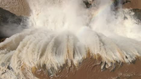 dramatic descending view directly above powerful raging water falling over the edge