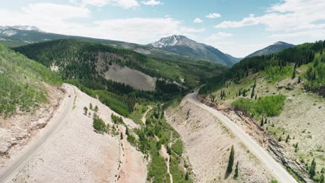 aerial push of a road that follows the mountains as a part of the san juan mountain range.
