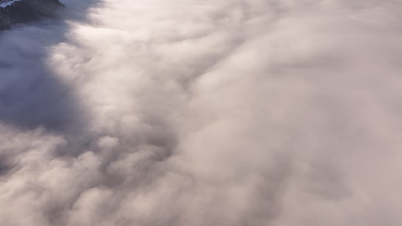 Thick fog in the mountains on a winter morning. Drone view of the Alpine heights in Switzerland
