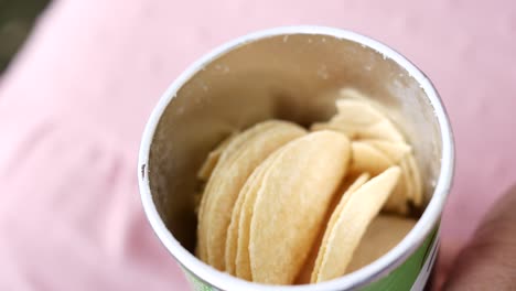 Hand-pick-potato-chips-from-a-container-,