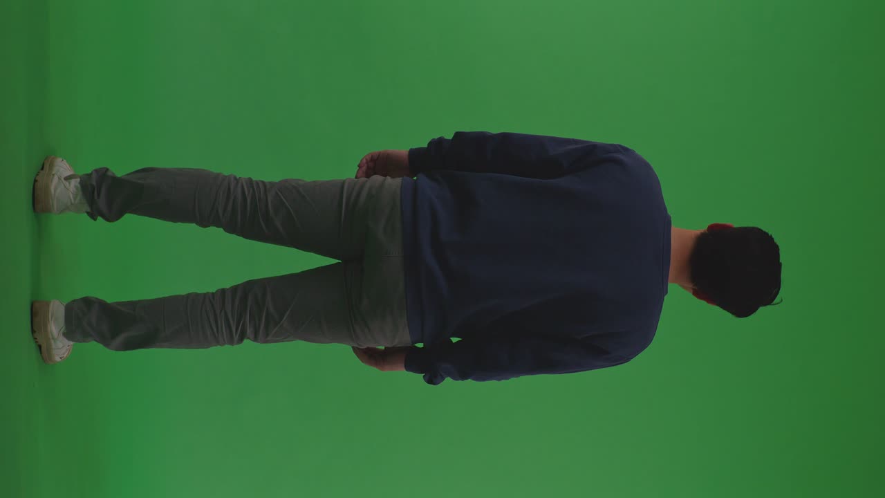 Full Body Back View Of Asian Refugee Male Shaking His Head Being Sad Due To The War While Standing On The Green Screen Background