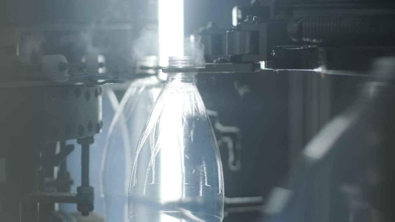 Automatic filling machine pours water into plastic PET bottles at modern beverage plant