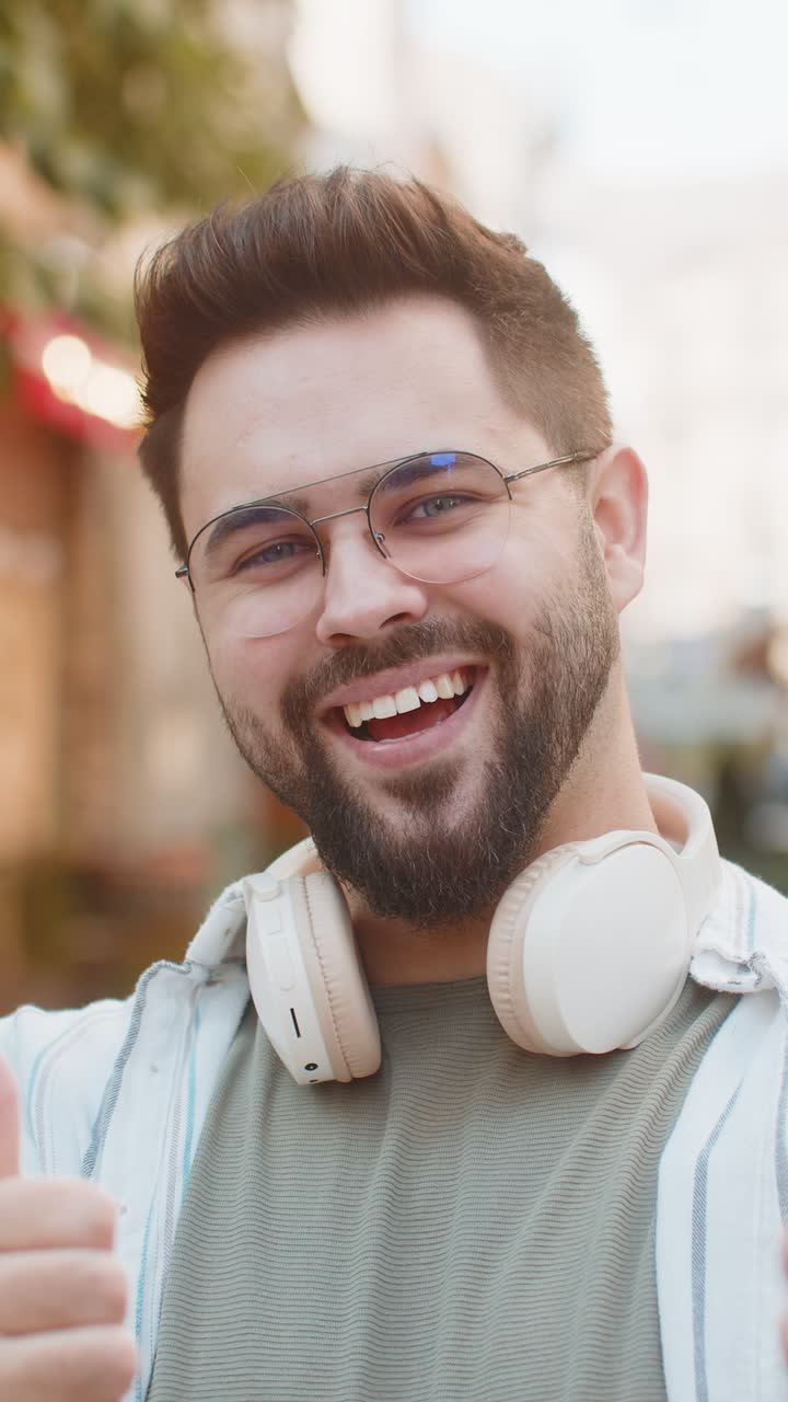 giovane uomo caucasico allegro che mostra due pollici in alto dà una risposta positiva in piedi sulla strada della città