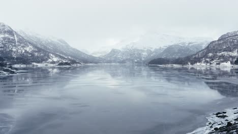 Flying-above-a-frosen-lake-between-Mountains-in-fogy-day-in-Norway-in-december-2018