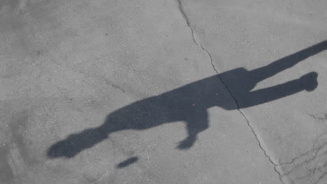 the shadow of a man juggling balls is seen on the sidewalk