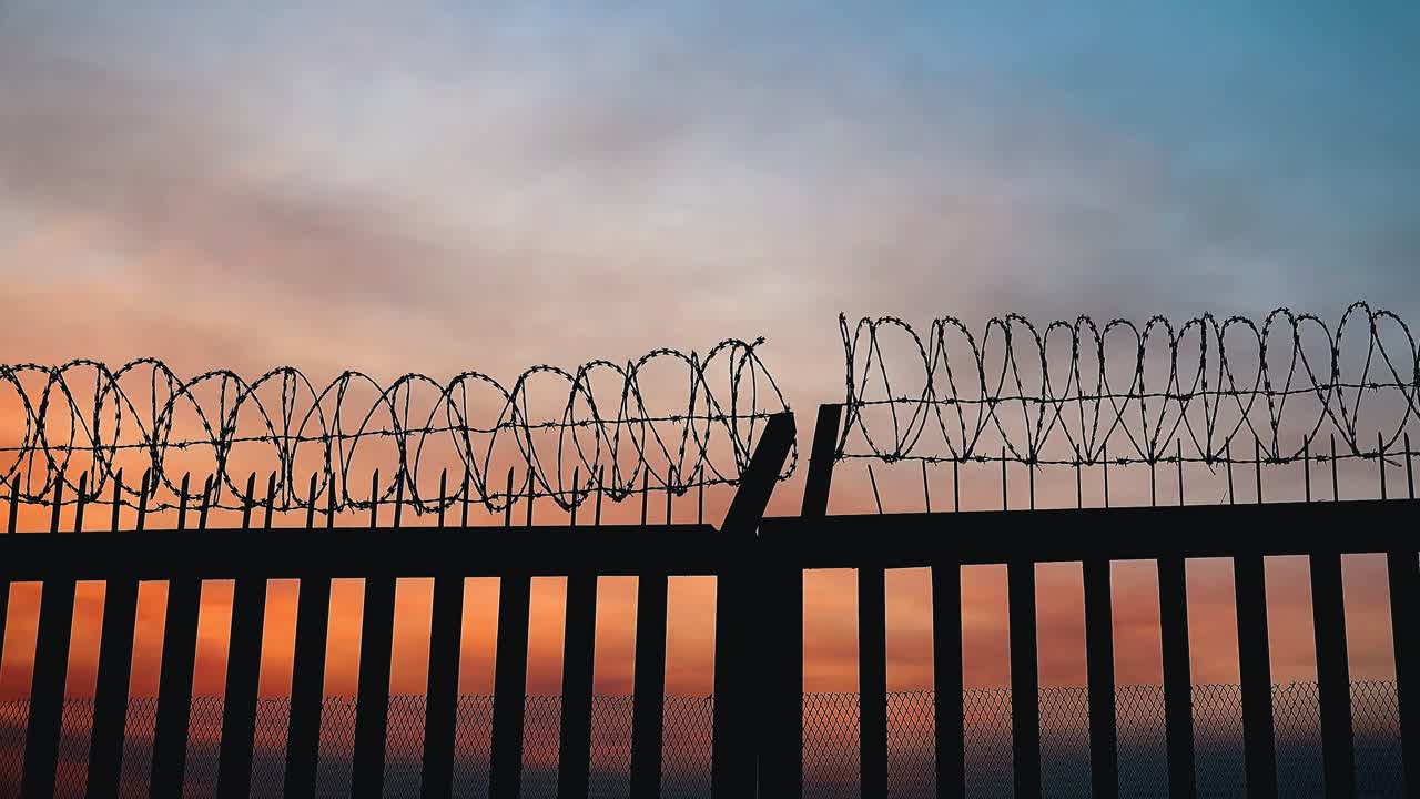 nubes de puesta de sol de lapso de tiempo moviéndose lentamente a través del cielo sobre una silueta de cerca de alambre de púas