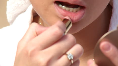 Close-up-of-a-young-woman-putting-lipstick