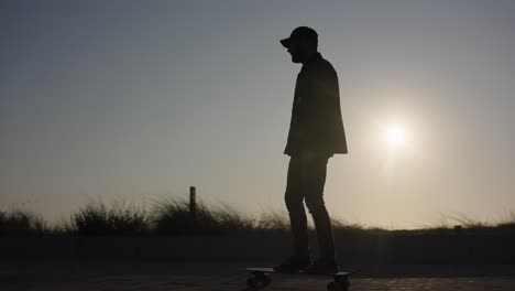 cool skateboarder cruceros por el camino, sol retroiluminado creando silueta