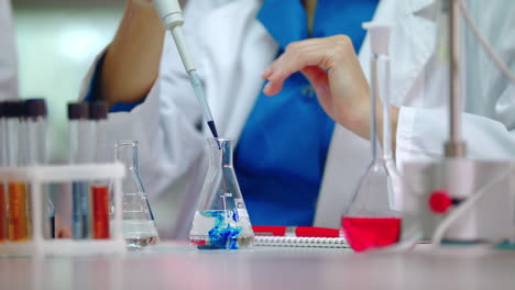 female scientist pouring reagent in lab flask. scientist doing chemical reaction