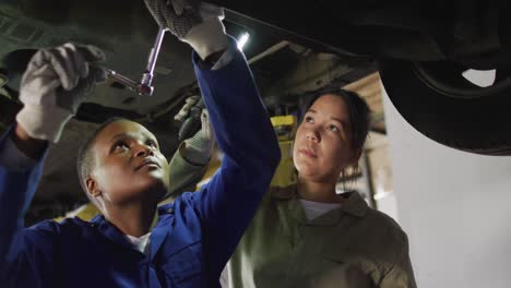 video of two diverse female car mechanics repairing car