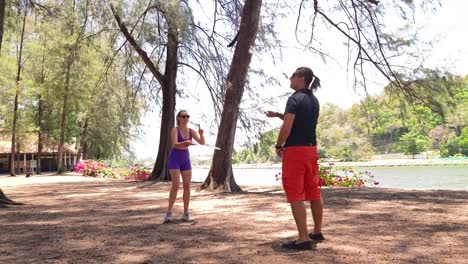couple playing badminton in a park by a lake
