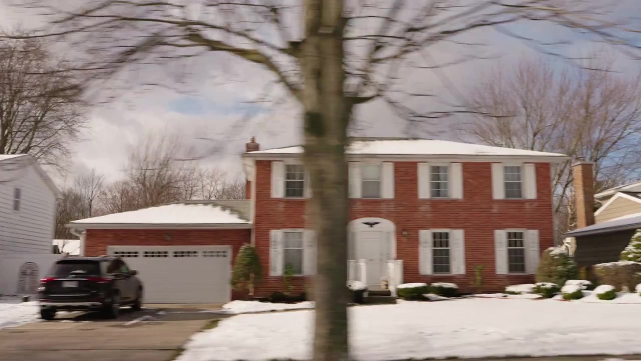 Moving View of Snowy Suburban Homes and Bare Trees