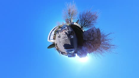 little tiny planet 360 small world view of a man walking past buildings towards a church in 4k