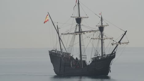 ferdinand magellan nao victoria carrack boat replica with spanish flag sails in the mediterranean at sunrise in calm sea side shot in slow motion 60fps