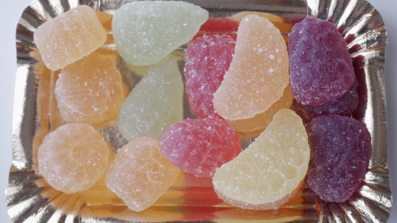 Colorful candies on tray, person picking a treat, sweet and joyful moment