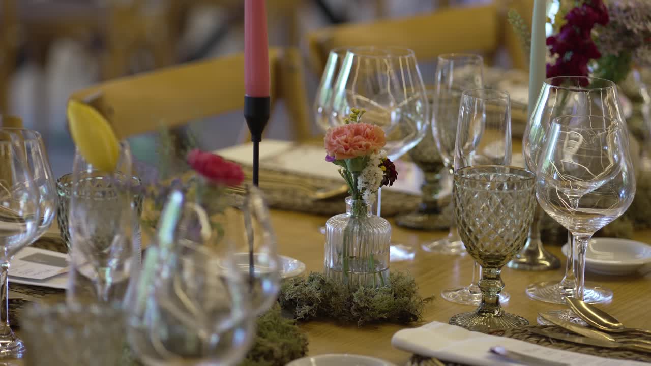 Close up of rustic wedding table with elegant glassware, candles, and floral decor